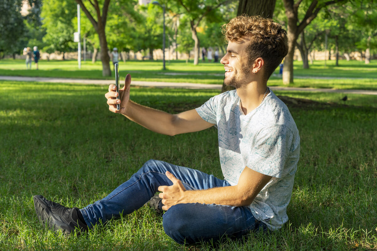 자신의 전화를 사용하여 비디오를 녹음하는 공원에서 남자
