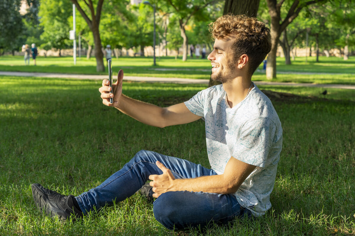 Uomo al parco registrando un video usando il suo telefono