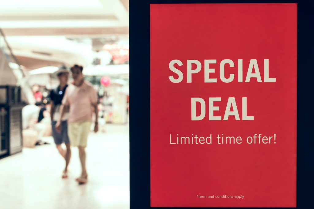 Special deal promo sign to the right of blurred people in shopping setting